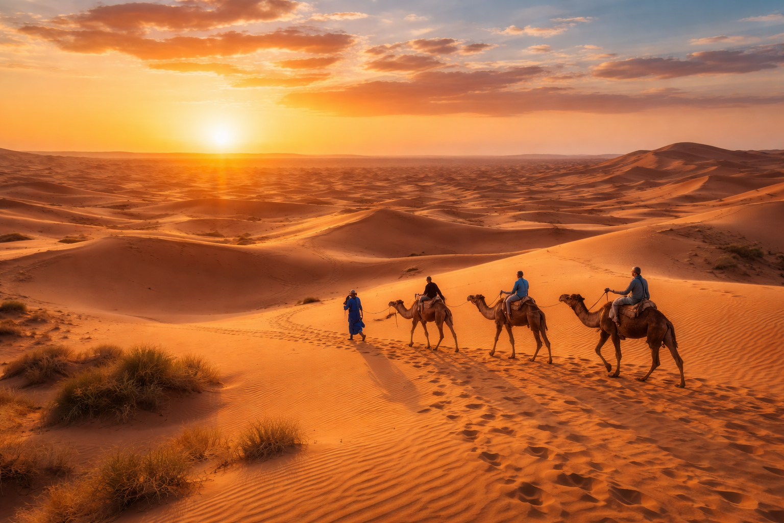 carovana di cammelli nel Deserto del Sahara al tramonto con dune dorate e cielo arancione viaggio in Marocco